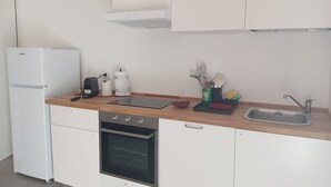 A modern kitchen with a refrigerator, oven, sink, and countertop with various appliances and utensils.