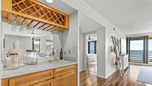 Una cocina moderna con armarios de madera, un botellero y un amplio ventanal con vistas al océano.