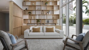 A modern living room with a white sofa, two armchairs, and a wooden shelving unit filled with decorative items. - Royal Beach Hotel Punta Cana A Jdv By Hyatt Hotel (Punta Cana)