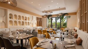 A modern restaurant with multiple dining tables, comfortable seating, and a view of greenery outside. - Royal Beach Hotel Punta Cana A Jdv By Hyatt Hotel (Punta Cana)