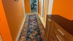 Um corredor com paredes laranja, carpete estampado e um arm ário de madeira.