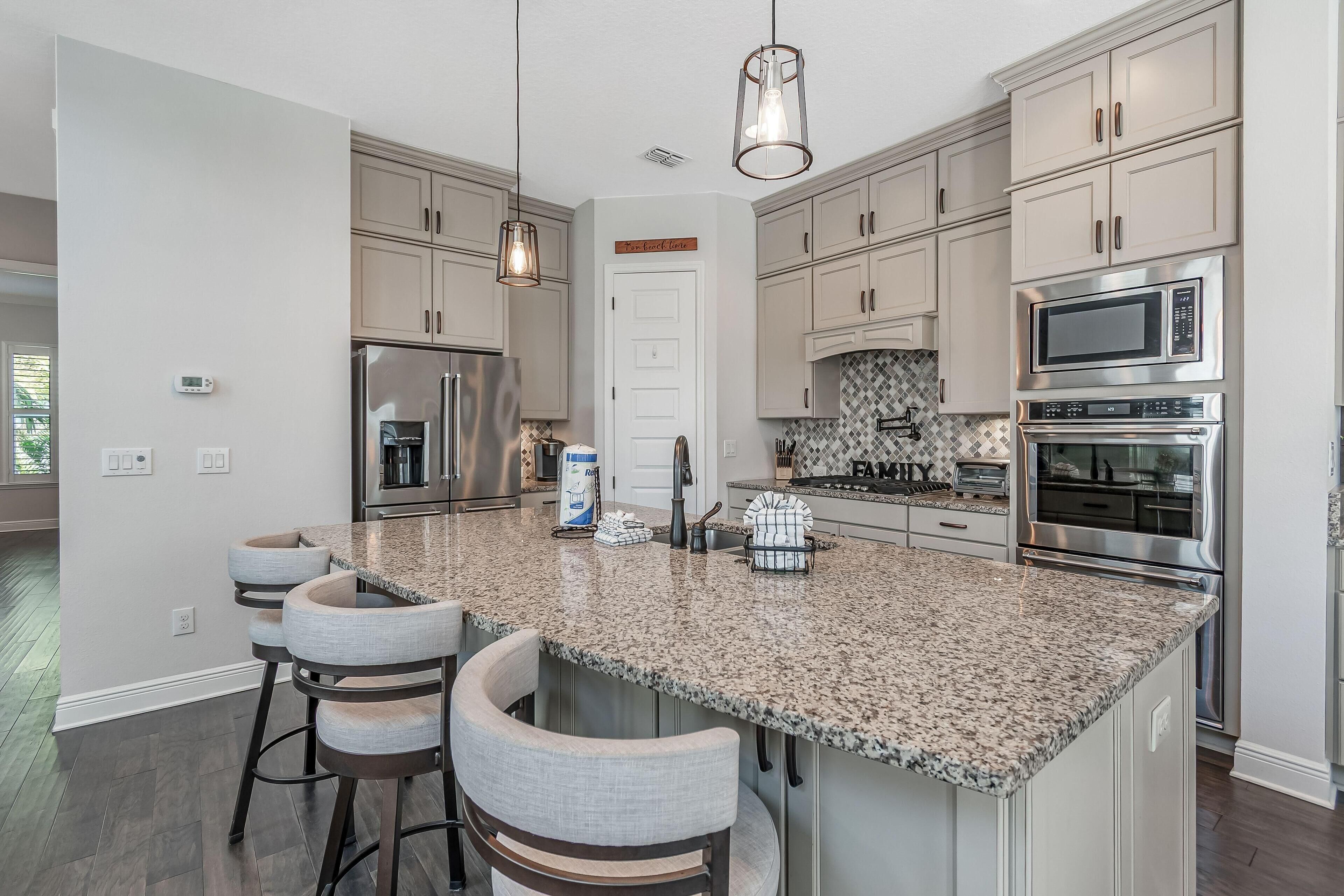 A modern kitchen with granite countertops, stainless steel appliances, and light-colored cabinetry.