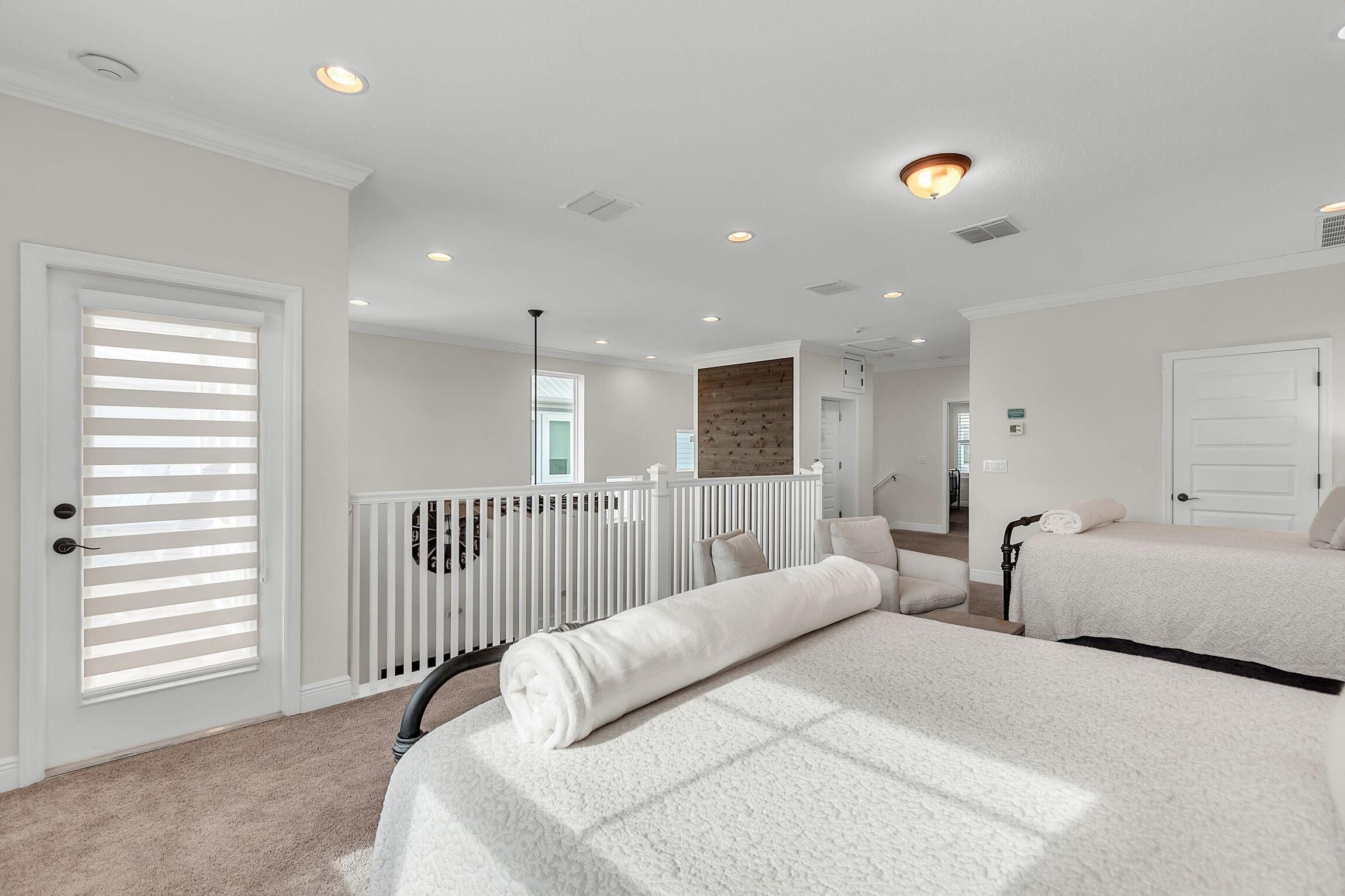 A hotel room with a large bed, a white door, and a view of the hallway.