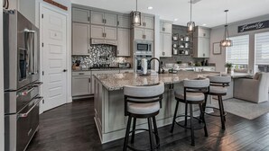 A modern kitchen with granite countertops, stainless steel appliances, and a central island with bar stools.