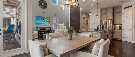 A spacious kitchen with a large island, modern appliances, and a dining area with a wooden table and cushioned chairs.