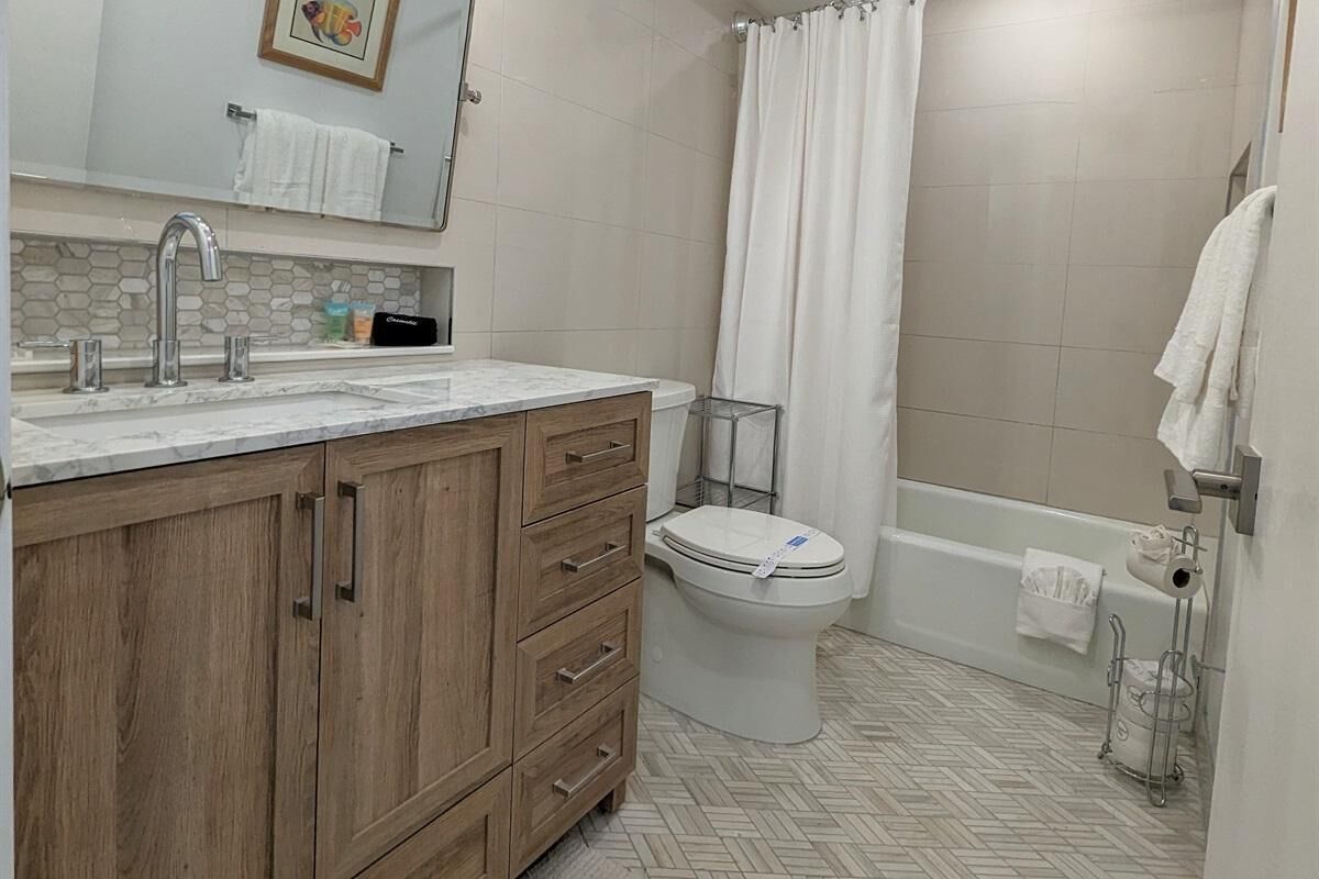 Une salle de bain avec un meuble-lavabo en bois, un évier, des toilettes et un espace douche.
