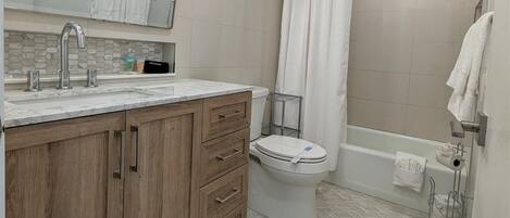 Une salle de bain avec un meuble-lavabo en bois, un évier, des toilettes et un espace douche.