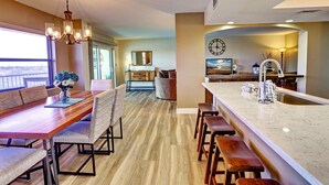 A modern kitchen with a large island, bar stools, and a dining area with a long table and chairs. - Bayshore Yacht & Tennis 806 (Indian Shores)