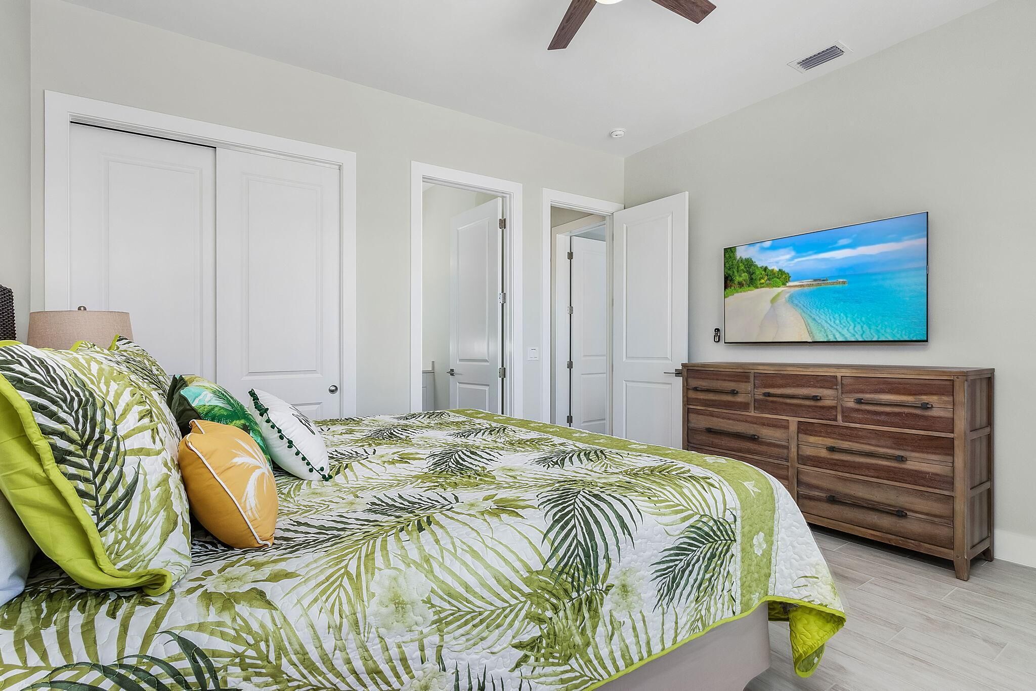 A bedroom with a bed, a dresser, and a TV on the wall.