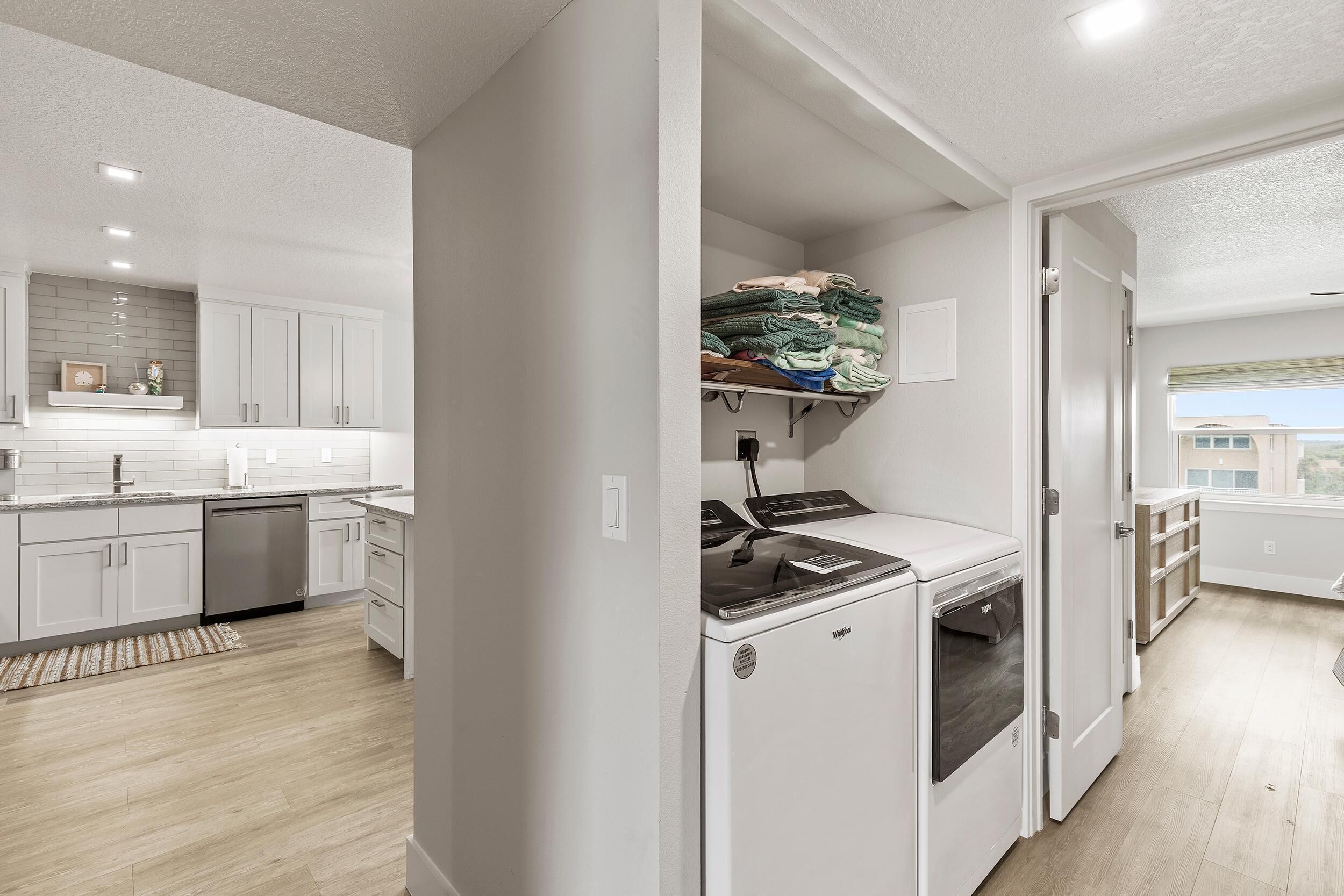 A modern kitchen with white cabinetry, a built-in dishwasher, and a compact refrigerator.