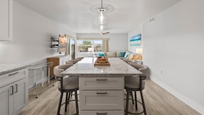 A modern kitchen with a central island, bar stools, and a ceiling fan. - Seaward B503 (New Smyrna Beach)