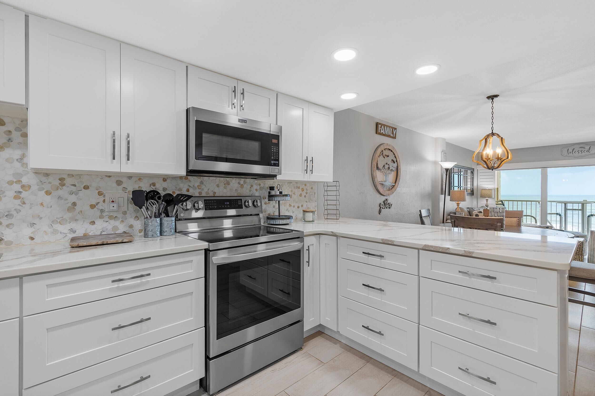A modern kitchen with white cabinetry, stainless steel appliances, and a decorative backsplash.