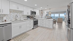 A modern kitchen with white cabinets, stainless steel appliances, and a view to the outside. - Ponce de Leon Towers 804 (New Smyrna Beach)