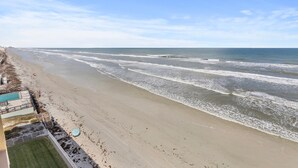 A beach with waves, a pool, and umbrellas. - Ponce de Leon Towers 804 (New Smyrna Beach)