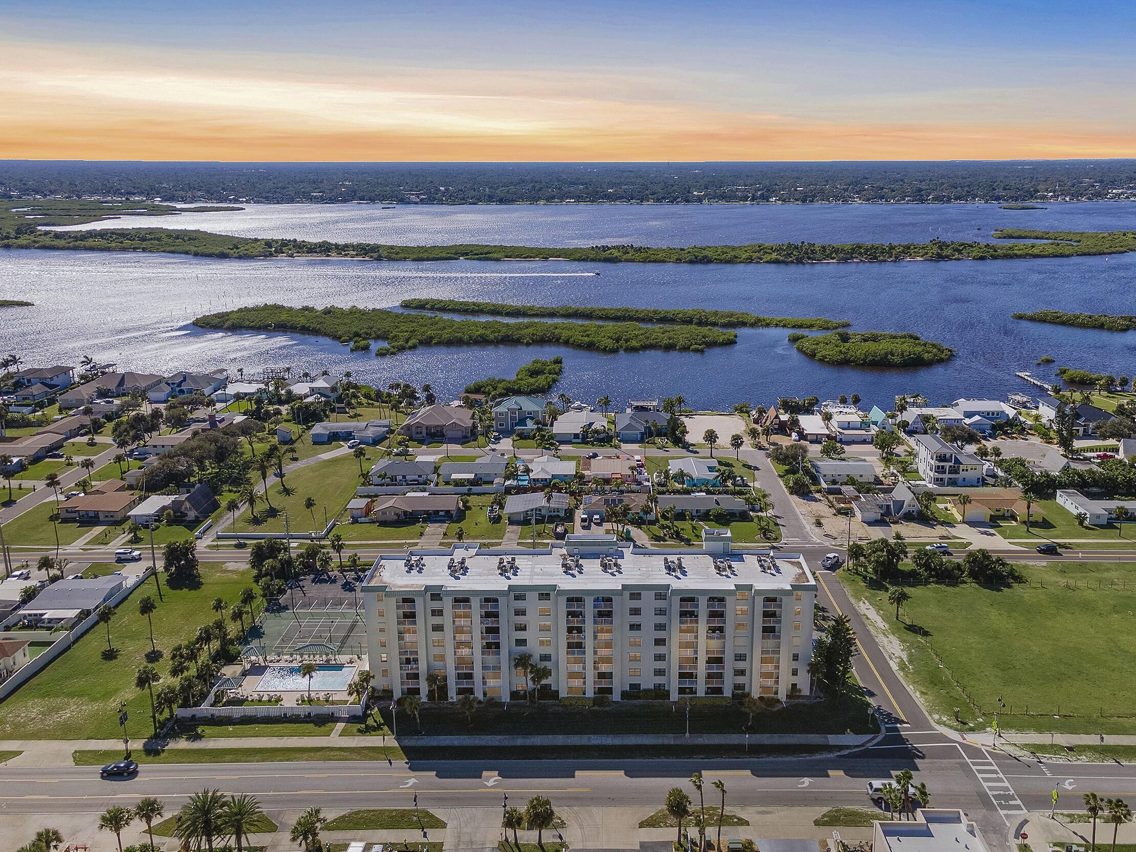 Un hôtel situé sur la côte, doté d’une cour intérieure, de plusieurs étages et offrant une vue sur l’eau et la végétation environnantes.