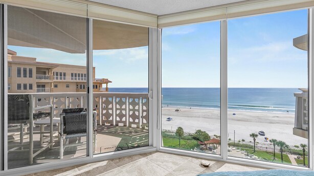 A balcony with a view of the beach and ocean.