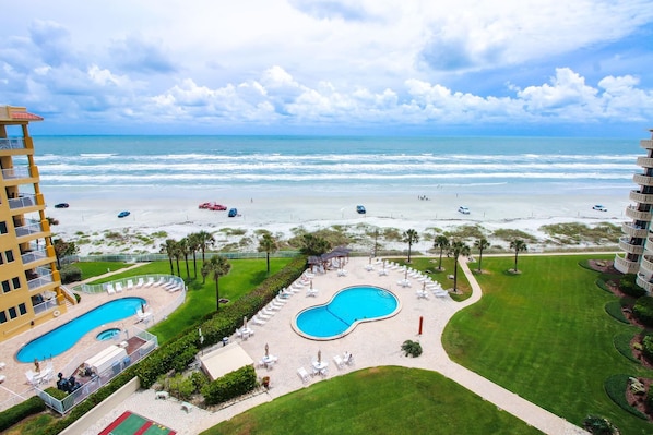Relax by the resort's central pool surrounded by lounge areas and a lush lawn, with access to the beach.