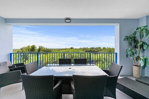 Ein Balkon mit Tisch und Stühlen, einem Blumentopf und Blick auf Grün.