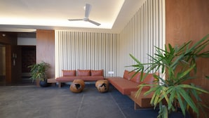 Un vestíbulo moderno con un sofá modular, dos mesas redondas de centro y plantas en macetas.