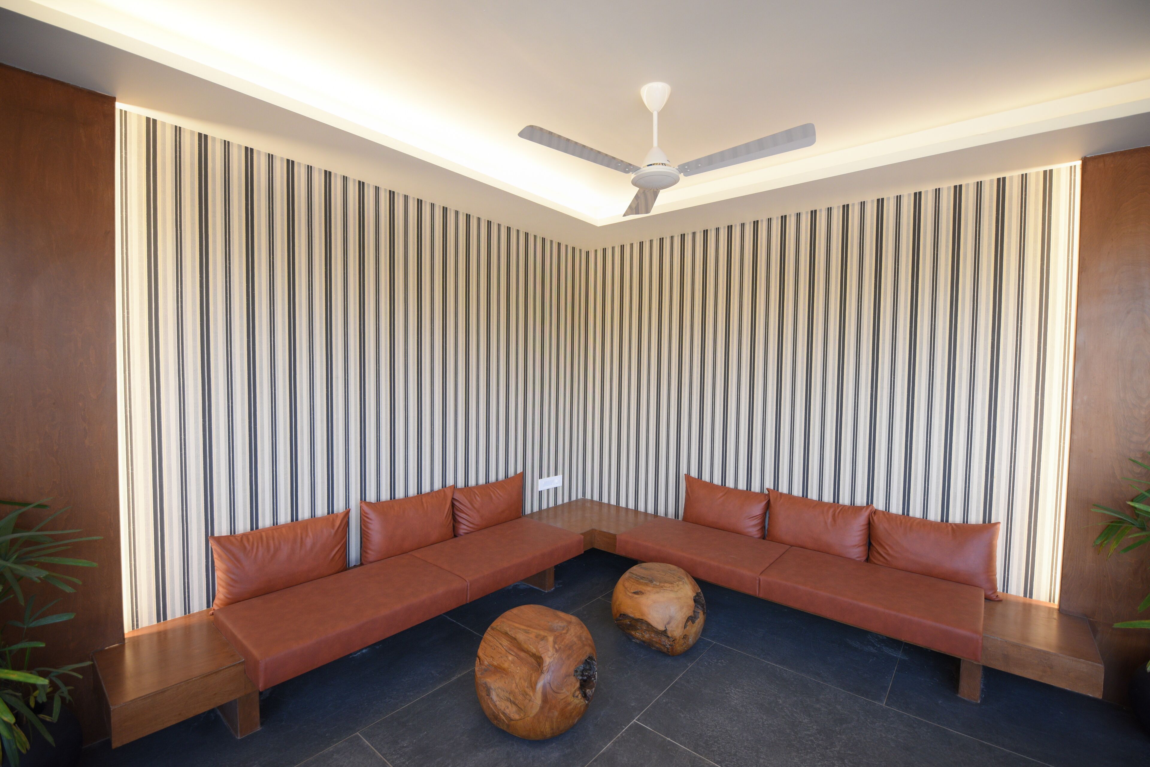 Ein modernes Wohnzimmer mit einer Eckcouch, zwei Holztischen und einem Deckenventilator.