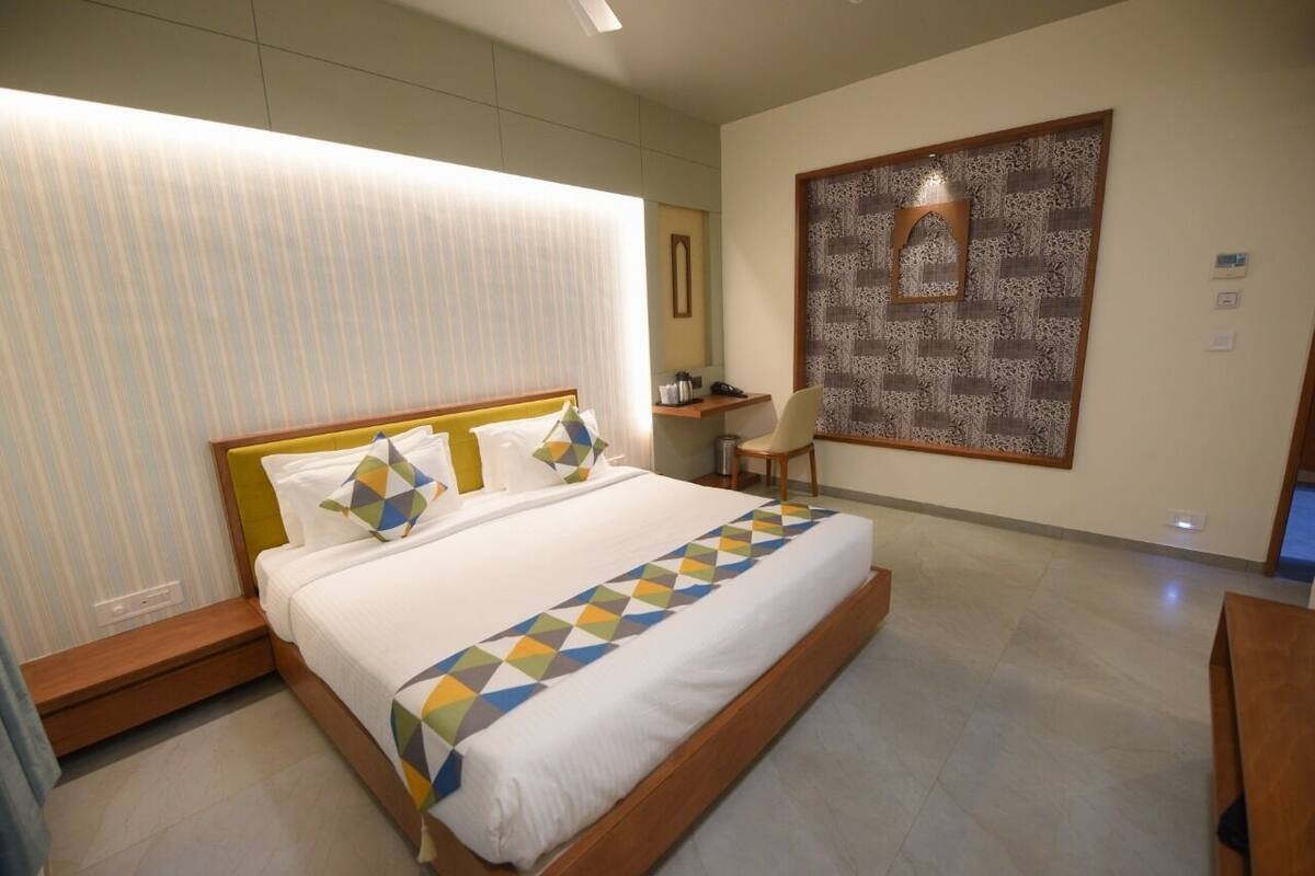 Una habitación de hotel moderna con una cama grande, un escritorio y un elemento decorativo en la pared.
