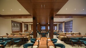 Un restaurante amplio con varias mesas y sillas, con un diseño moderno y detalles de madera y sillas color turquesa.