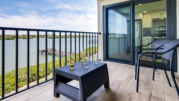 Un balcon donnant sur un lac, une table avec des verres et une chaise.