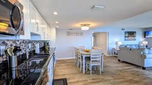 Une cuisine moderne avec des meubles blancs, une cuisinière noire et un coin repas comprenant une table et des chaises en bois.