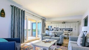 Un salon avec un canapé, une table basse et un tapis à motifs. Une porte-fenêtre coulissante donne accès à un balcon.