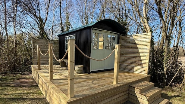 Un pontile in legno con una piccola struttura tipo chalet, circondato da una ringhiera in corda.