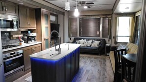 A compact kitchen with a central island, built-in appliances, and a cozy seating area with a sofa and a coffee table. - Charming RV Hideaway campground in Key Largo; Sun & Fun! (Key Largo)