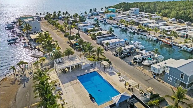 A coastal resort with a swimming pool, beachfront villas, and boats docked along the shore. - Charming RV Hideaway campground in Key Largo; Sun & Fun! (Key Largo)