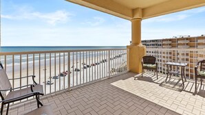 A balcony with a view of the beach, a table, and two chairs. - Atlantic Villas 601 (New Smyrna Beach)