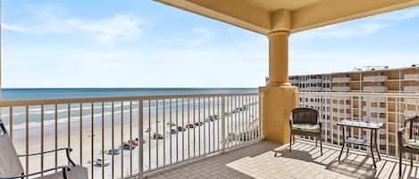 Een balkon met uitzicht op het strand, een tafel en twee stoelen.