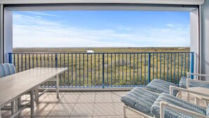 Un balcon avec une table et des chaises, d’où l’on peut admirer un paysage verdoyant.