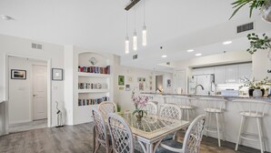 Une cuisine moderne avec des meubles blancs, un îlot central et des tabourets de bar.