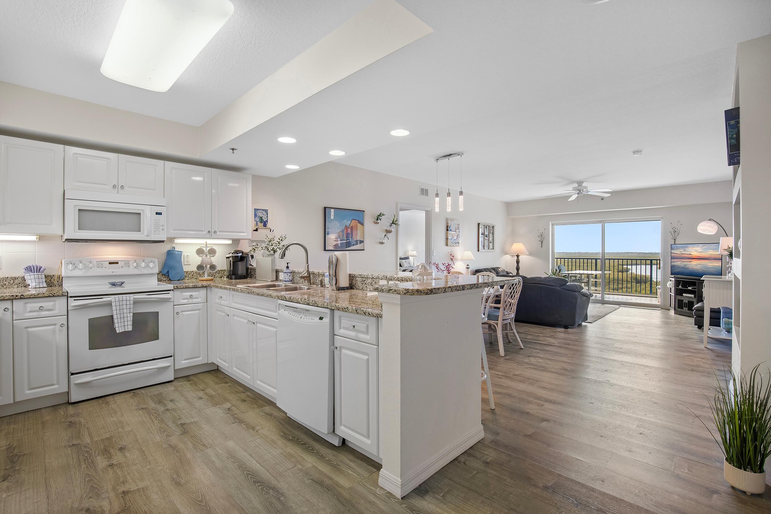 A modern kitchen with white cabinets, a built-in oven, and a large island with a granite countertop.