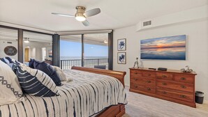 Un dormitorio con cama, cómoda, ventilador de techo y un amplio ventanal con vistas.