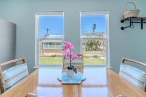 A dining area with a wooden table, chairs, and a potted orchid.