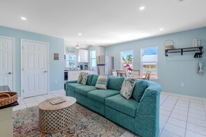 A living room with a teal sofa, a coffee table, and a patterned rug. - Island Paradise 3 (Fort Myers Beach)