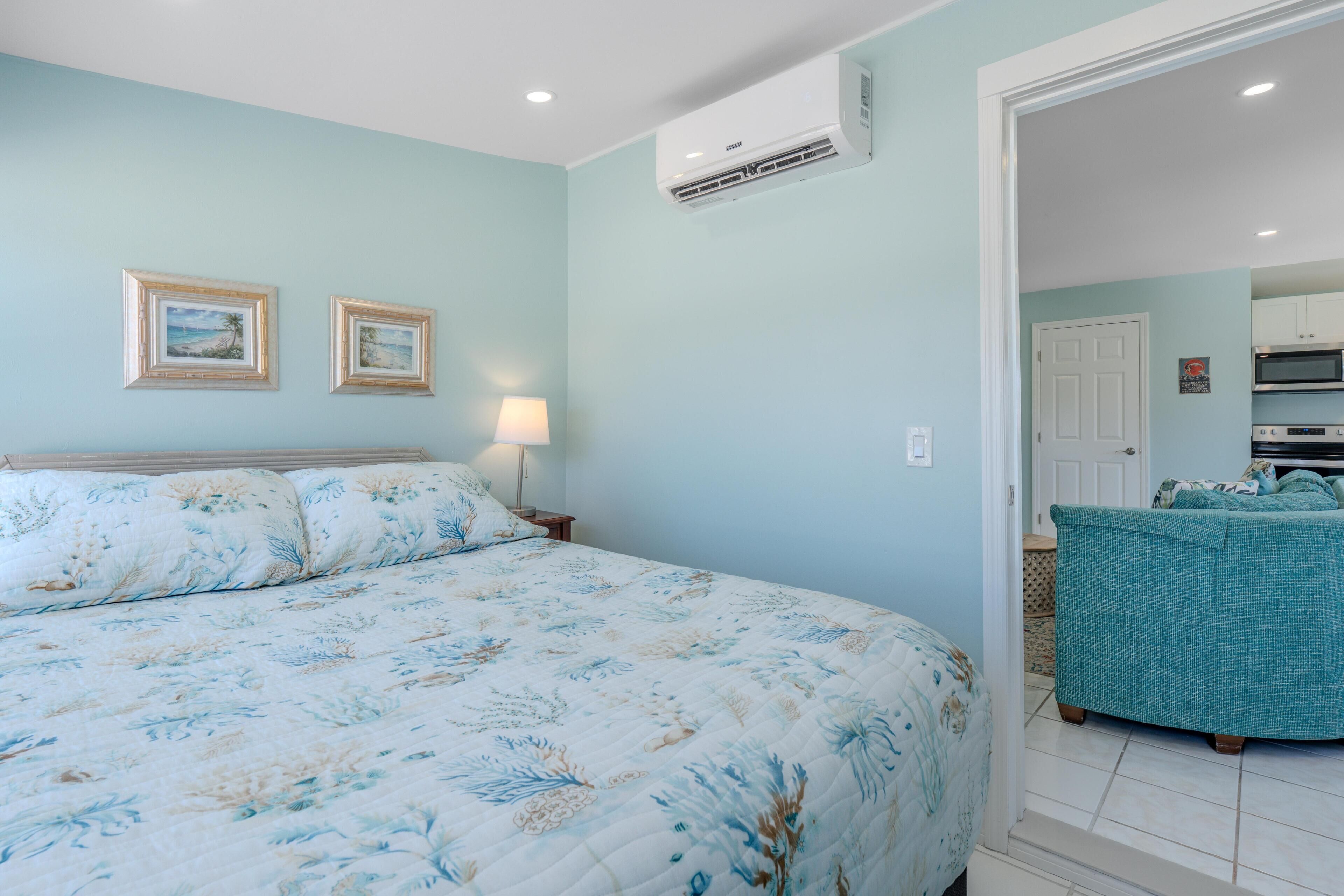 Un dormitorio con una cama, una mesita de noche, una lámpara y dos cuadros en la pared.