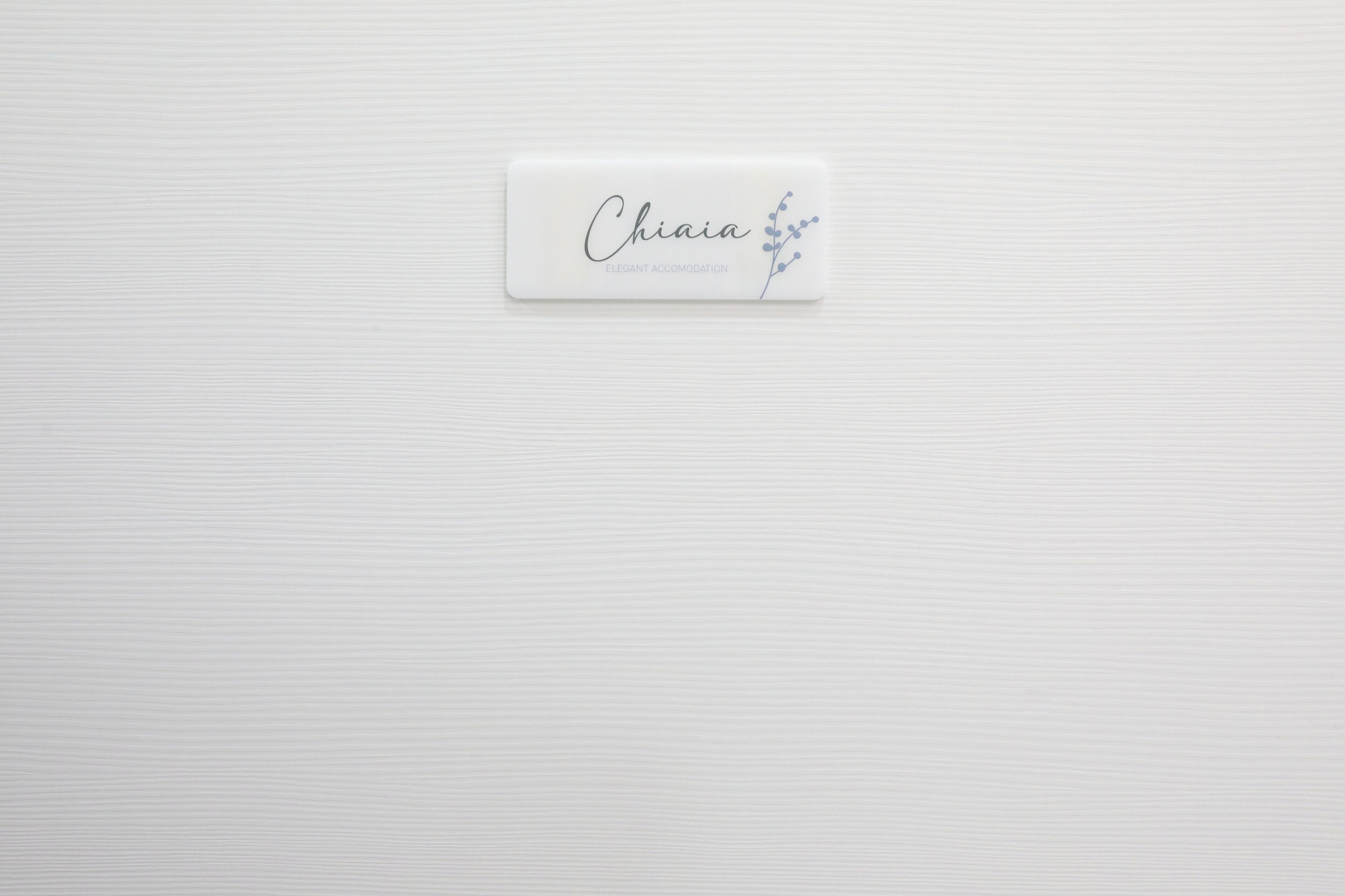 A white business card with the name "Chiaia" and the tagline "ELEGANT ACCOMMODATION" on a textured white background.