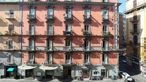 A multi-story hotel with balconies, a ground-floor bar, and a visible entrance. - VivimiHome - CharmiNaples (Naples)