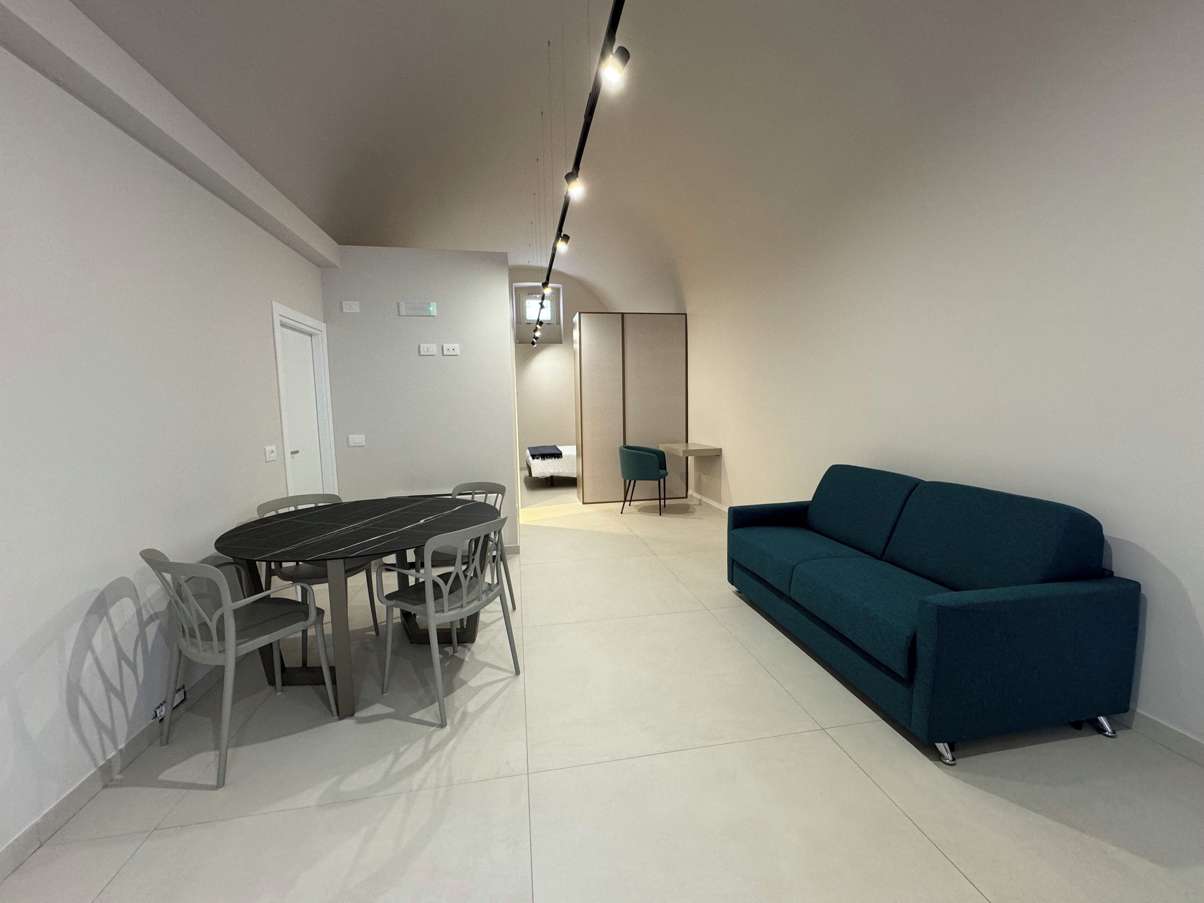 Una sala de estar moderna con una mesa de comedor y sillas, un sofá y una zona de cocina al fondo.