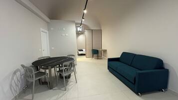 Una sala de estar moderna con una mesa de comedor y sillas, un sofá y una zona de cocina al fondo.
