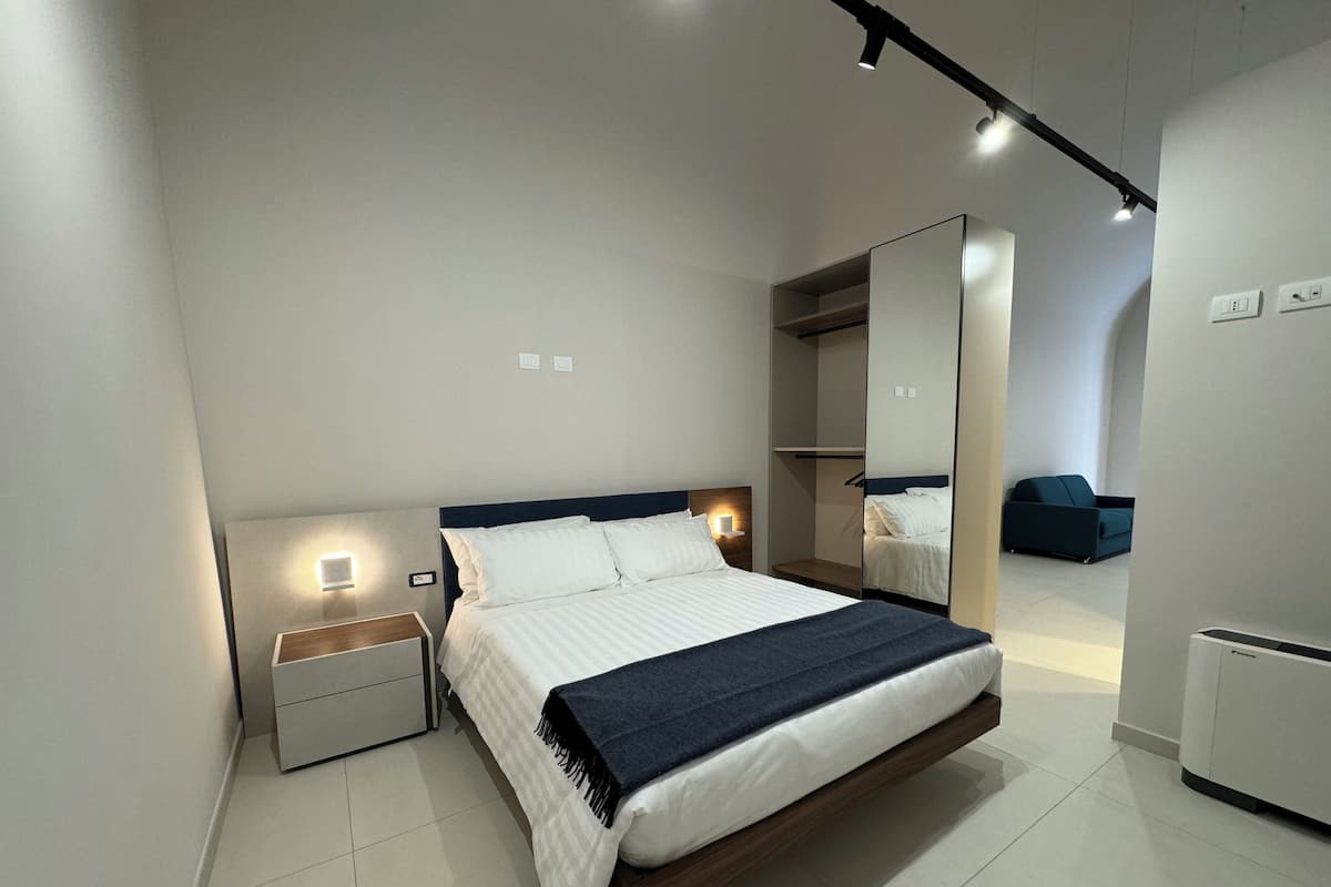 Ein modernes Schlafzimmer mit Bett, Nachttischen, einem Kleiderschrank und einem Spiegel.