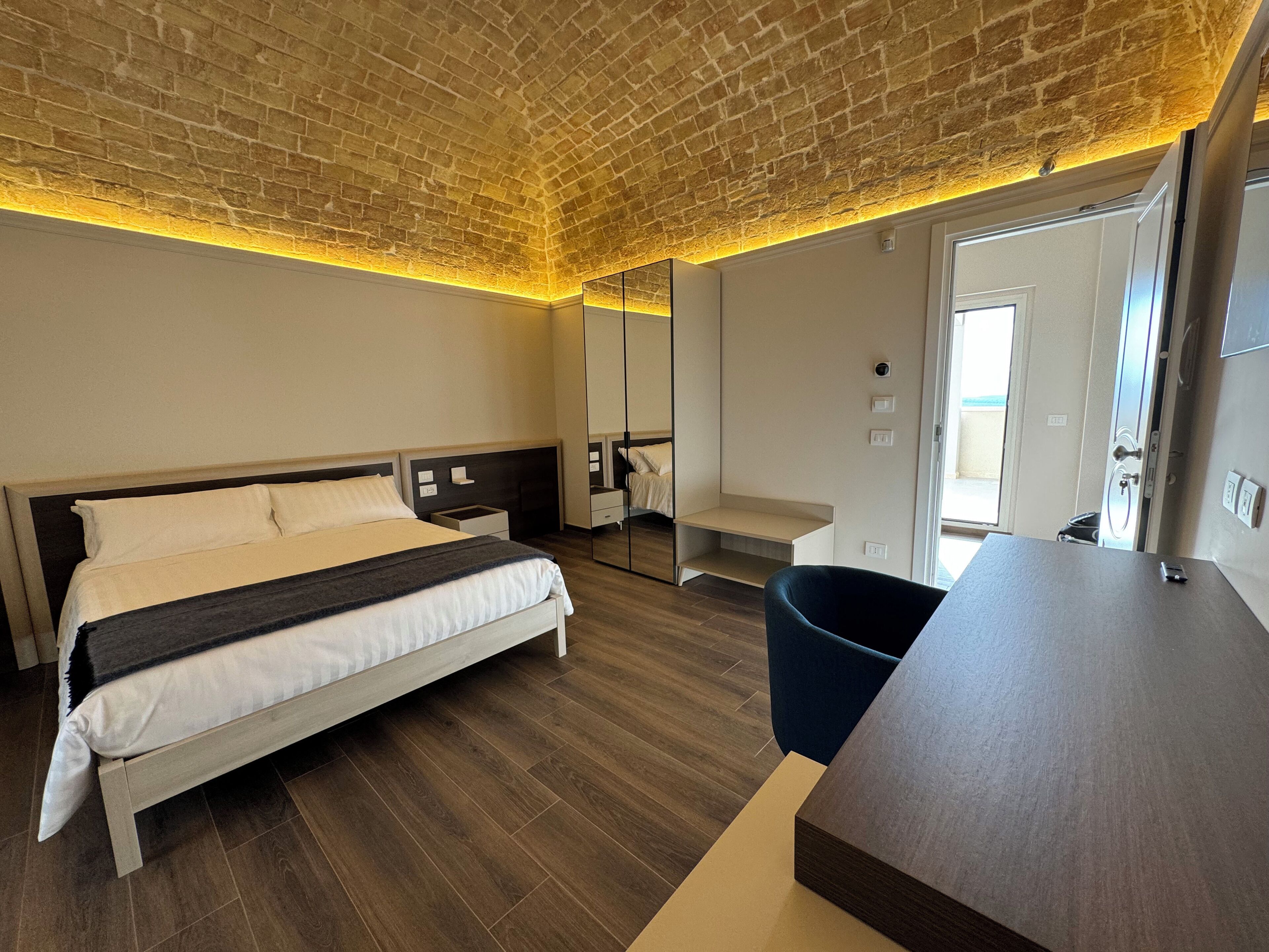 Una habitación de hotel moderna con una cama grande, un escritorio, una silla y un espejo.