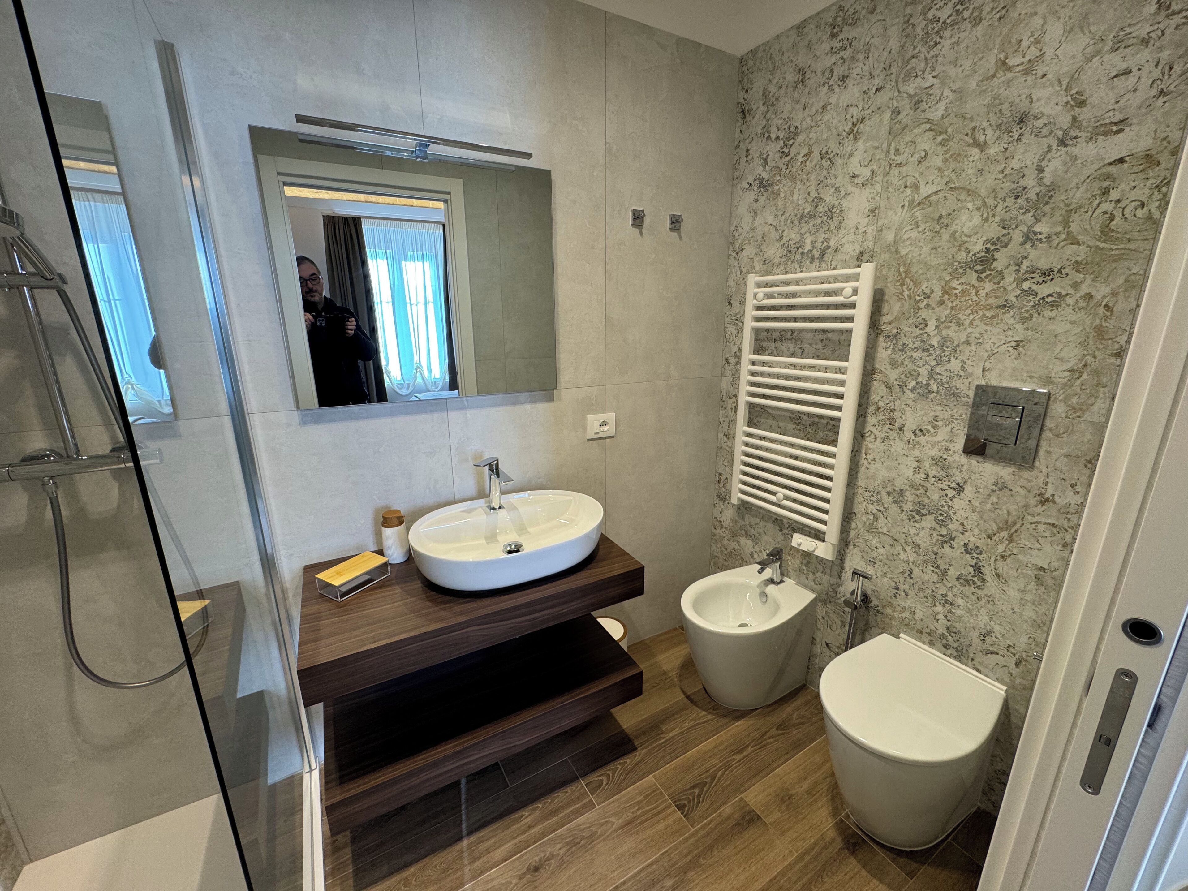 Un baño moderno con un espejo grande, un lavabo, un bidé y una ducha.