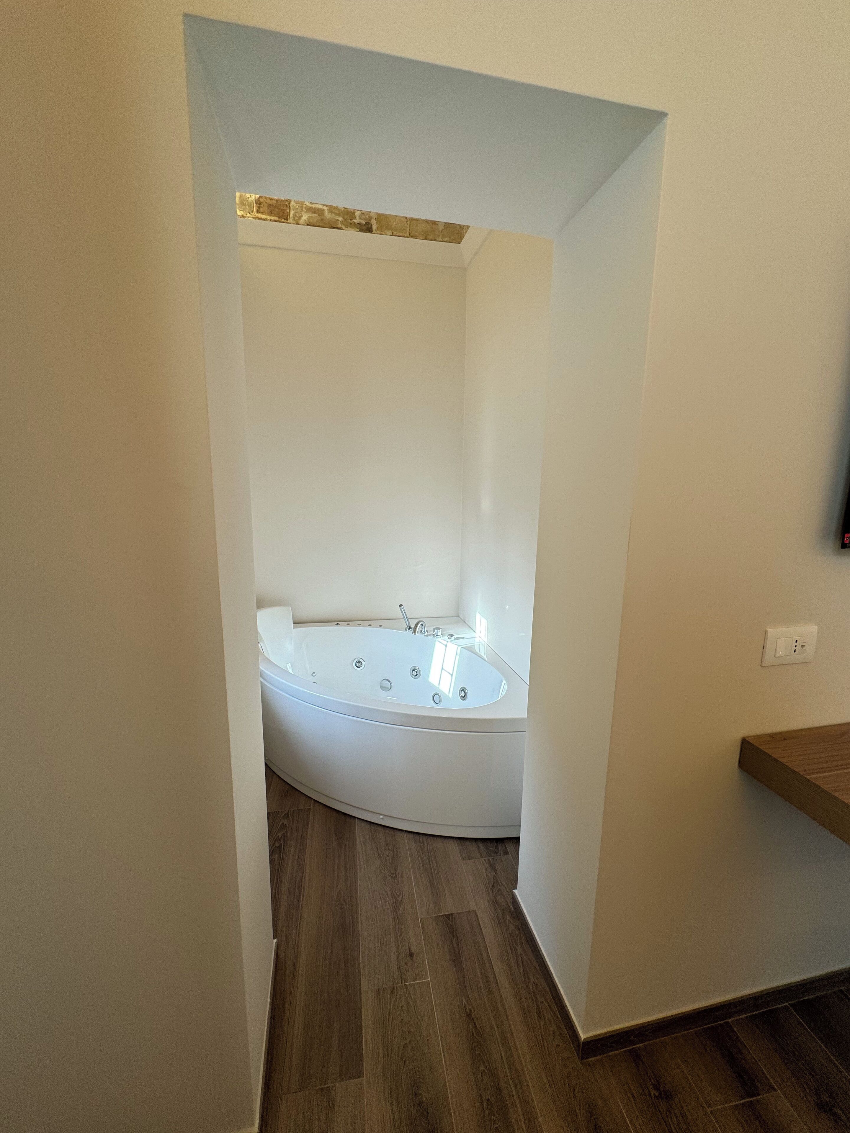 Un baño moderno con una bañera independiente, suelo de madera y un estante de madera.