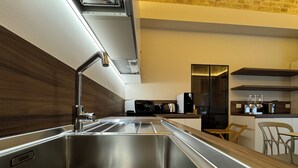A modern kitchen with a stainless steel sink, wooden panel backsplash, and contemporary appliances. - B&B PALAZZO CROGHAN (Torremaggiore)